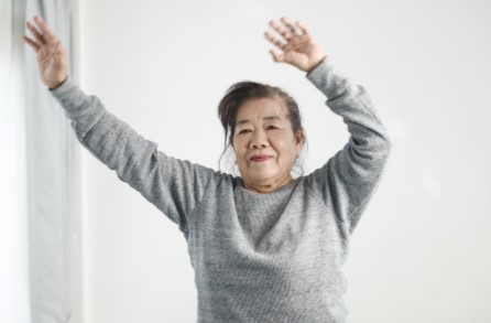A aged Asian woman excercising with her hands raised